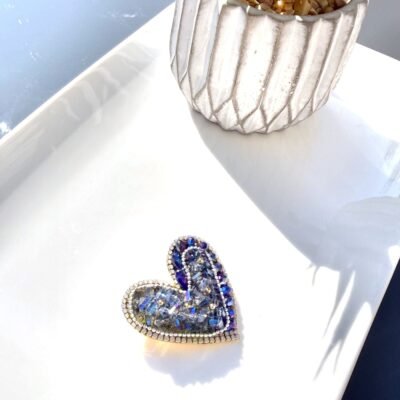 Broche cœur cristaux bleus posée sur un plateau blanc