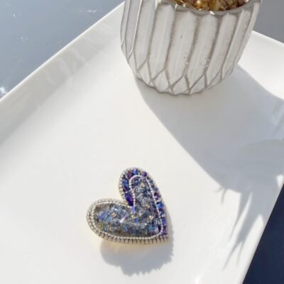Broche cœur cristaux bleus posée sur un plateau blanc