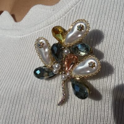Broche fleur éclatante portée sur un top blanc, gros plan sur les perles et cristaux
