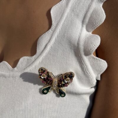 Broche papillon à cristaux et gouttes vertes portée sur un débardeur blanc