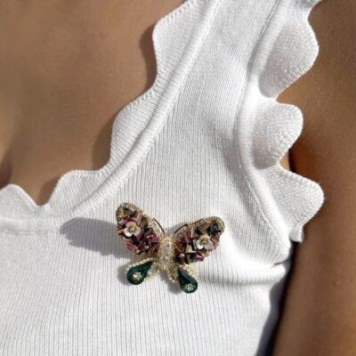 Broche papillon à cristaux et gouttes vertes portée sur un débardeur blanc