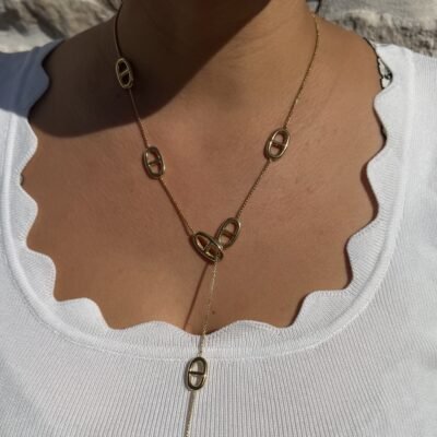 Collier cravate doré à maillons marins porté sur un haut blanc