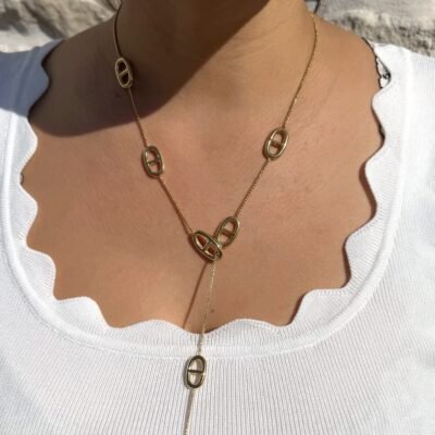 Collier cravate doré à maillons marins porté sur un haut blanc