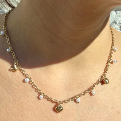 Collier doré à perles blanches pendantes et breloques cœur et papillon porté
