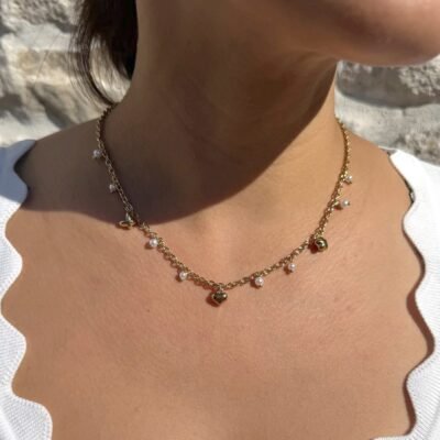 Collier perles blanches pendantes doré porté avec un haut blanc