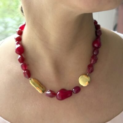 Collier pierre rouge doré porté au cou, perles rouges et deux pièces dorées