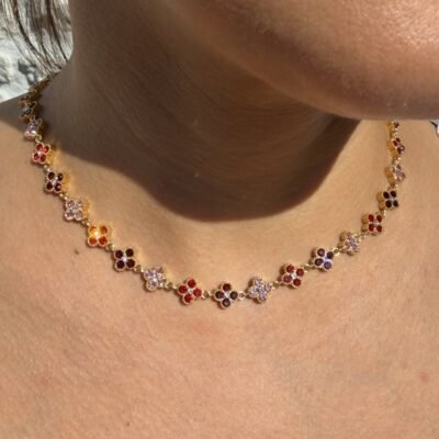 Collier rivière de trèfles dorés sertis de strass rouges et roses porté