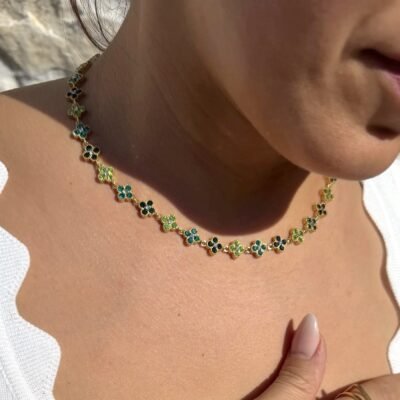 Collier trèfle vert doré porté avec un haut blanc