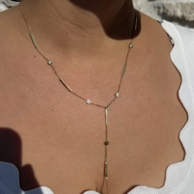 Collier en Y doré à barrettes et strass porté sur le décolleté