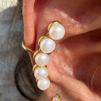 Gros plan sur l'ear cuff barrette de cinq perles serties de doré porté sur l'oreille
