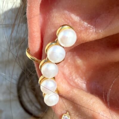 Gros plan sur l'ear cuff barrette de cinq perles serties de doré porté sur l'oreille
