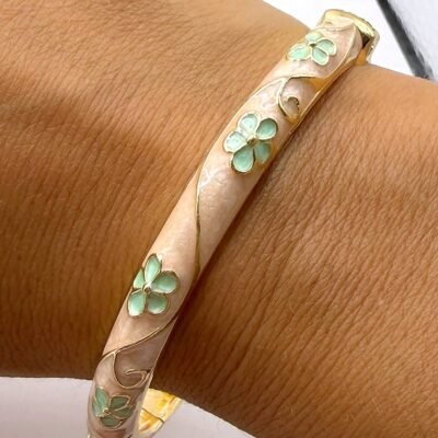 Bracelet jonc émaillé crème à fleurs vert d’eau porté au poignet, gros plan sur l’émail en relief
