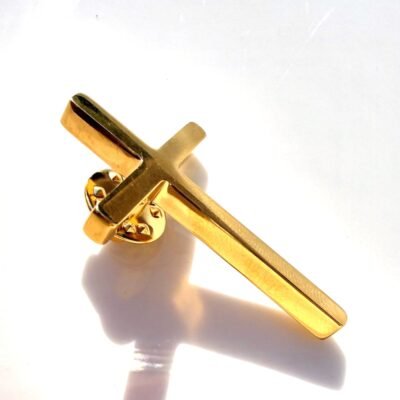 Pin's croix dorée posé sur fond blanc